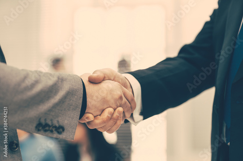 firm business handshake on a blurry office background.