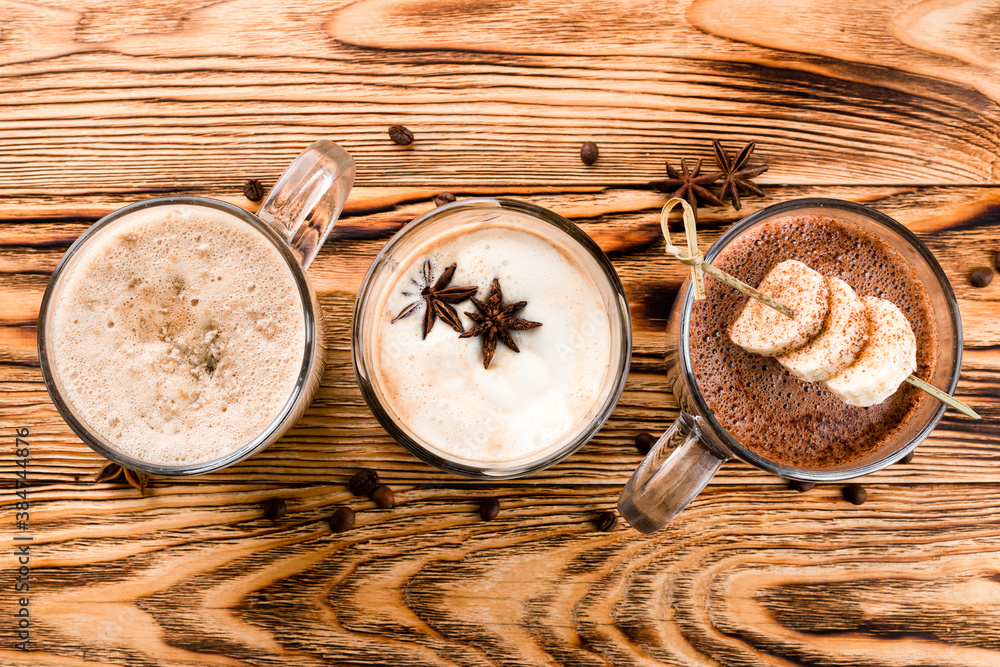 Hot chocolate with cinnamon sticks, anise, nuts and cocoa powder on rustic wooden background, top view Hot chocolate with cinnamon sticks, anise, nuts and cocoa powder on rustic wooden background, top view