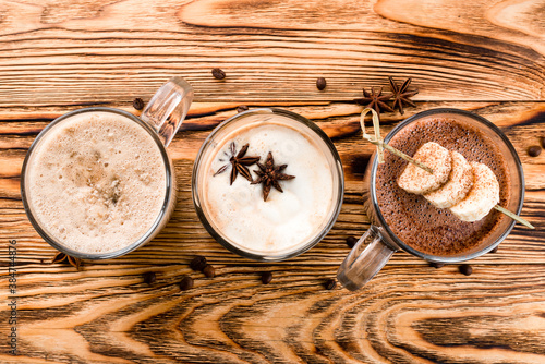 Fototapeta Naklejka Na Ścianę i Meble -  Hot chocolate with cinnamon sticks, anise, nuts and cocoa powder on rustic wooden background, top view