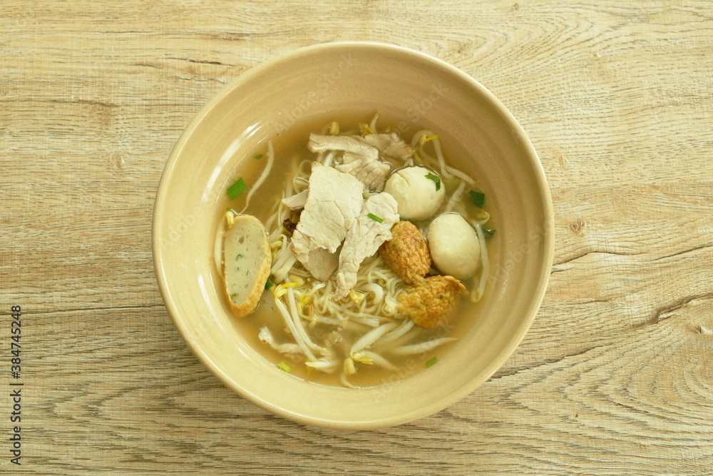 Chinese egg yellow noodles topping slice boiled pork and ball with soup in bowl Chinese egg yellow noodles topping slice boiled pork and ball with soup in bowl
