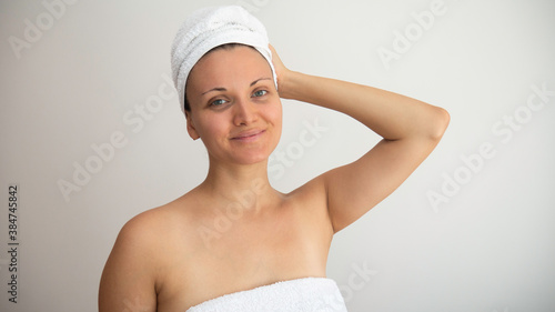 Woman without makeup wrapped in white towels.