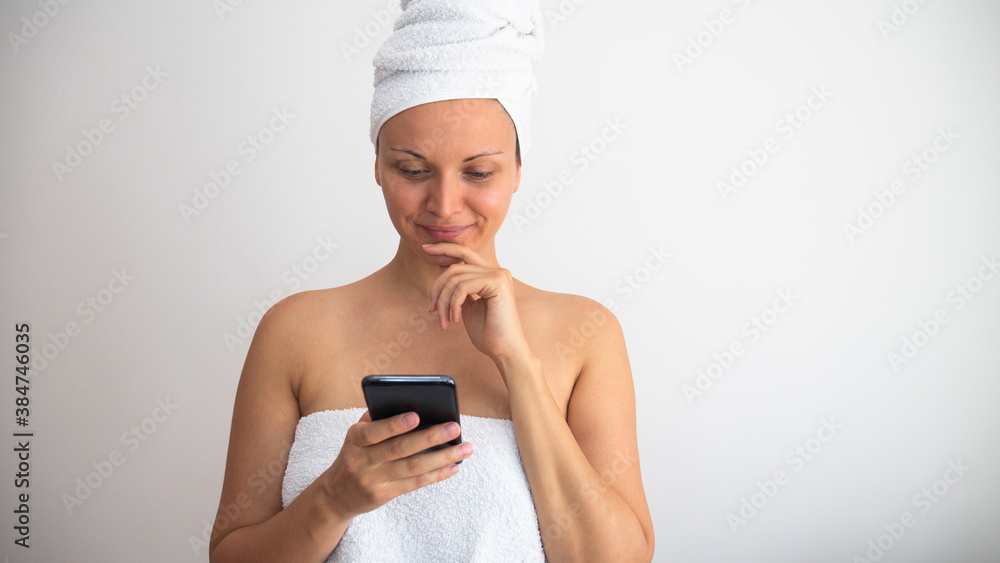 Woman after shower wrapped in a towels browsing on the phone. Woman after shower wrapped in a towels browsing on the phone.