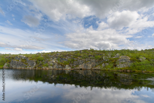 The reservoir is surrounded by hills and forest.Clouds are reflected in the water.Summer landscape.