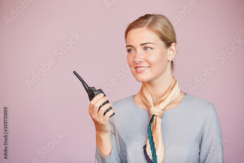 Canvas Print Waist up portrait of smiling flight attendant holding walkie-talkie while standi