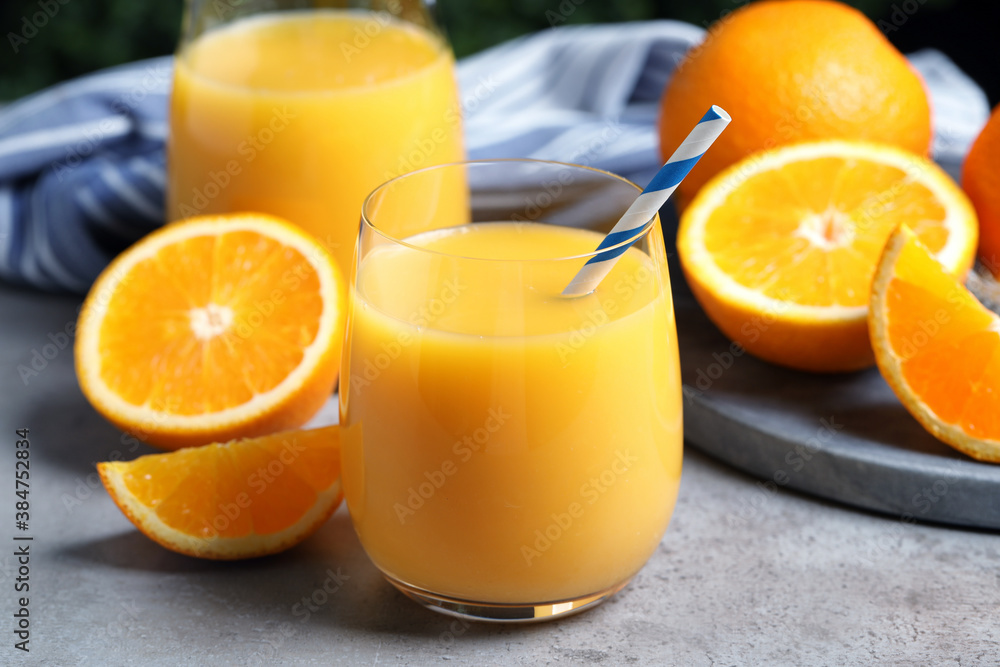 Glass of orange juice and fresh fruits on grey table, closeup Glass of orange juice and fresh fruits on grey table, closeup
