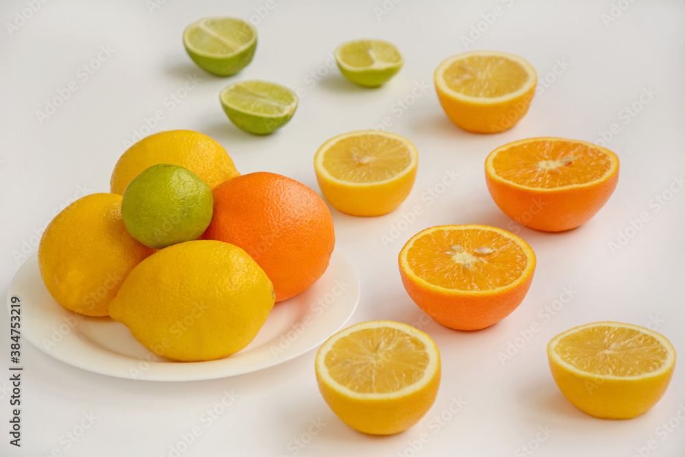 The layout of whole and sliced oranges, lemons, lime on a white plate The layout of whole and sliced oranges, lemons, lime on a white plate