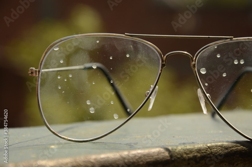 Water droplets on Eye glasses, green blurred background. 