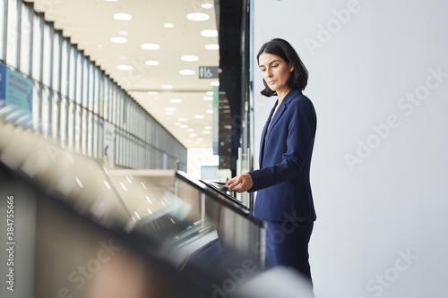 Photography Side view portrait of contemporary Middle-Eastern businesswoman swiping phone wh