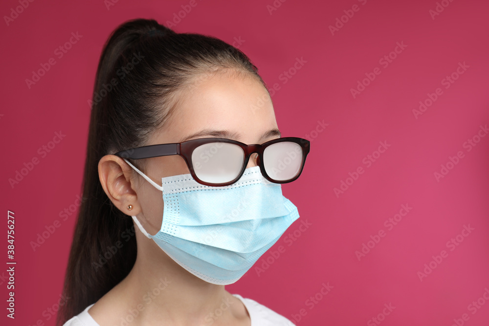 Little girl with foggy glasses caused by wearing medical face mask on pink background. Protective measure during coronavirus pandemic Little girl with foggy glasses caused by wearing medical face mask on pink background. Protective measure during coronavirus pandemic