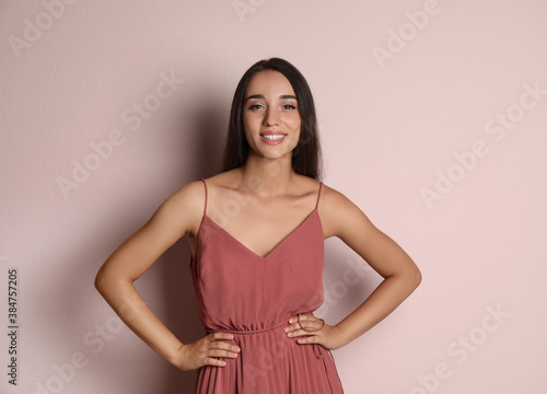 Young woman wearing stylish dress on pale pink background