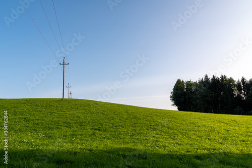 High-Voltage power line, Green Fields, Small Hills Countryside at sunset in Henndorf, Austria