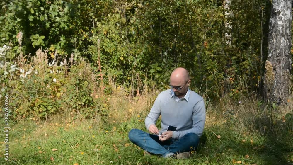Lonely man sits in the forest and takes notes in his notebook Lonely man sits in the forest and takes notes in his notebook