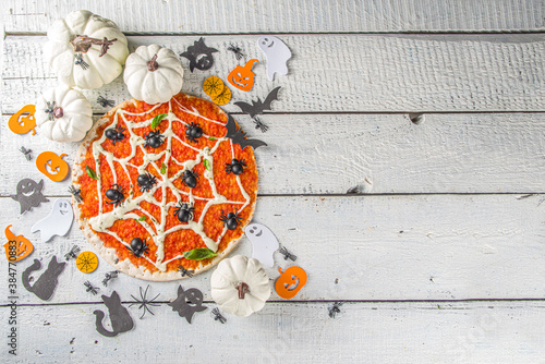 Halloween funny pizza. Halloween party recipe, Creative idea for Halloween pizza`s with ham and cheese ghosts, monster, spiders, white wooden background with Halloween decorations