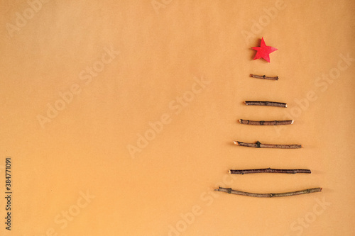 Creative sustainable eco Christmas tree made of wooden sticks and dry fruits and pine cones. Minimal design on craft paper background.