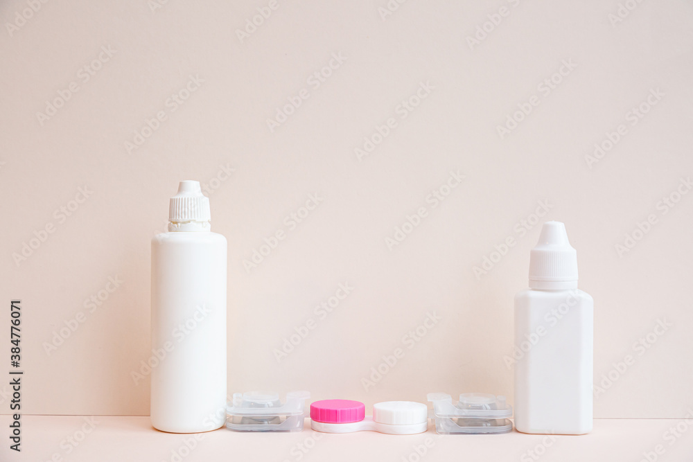 Contact lenses, lens solution and lens containers on a light pink background. Health care concept Contact lenses, lens solution and lens containers on a light pink background. Health care concept