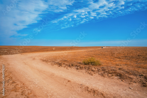 Sandy road to endless valleys against a blue sky with clouds