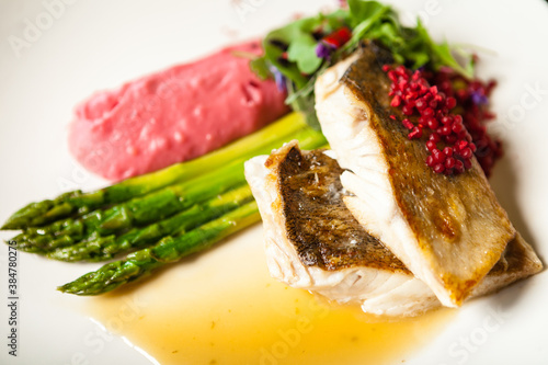Pike-perch fillet. Asparagus, pearl couscous, white wine sauce, beet-flavored mashed potatoes. Delicious seafood fish closeup served on a table for lunch in modern cuisine gourmet restaurant