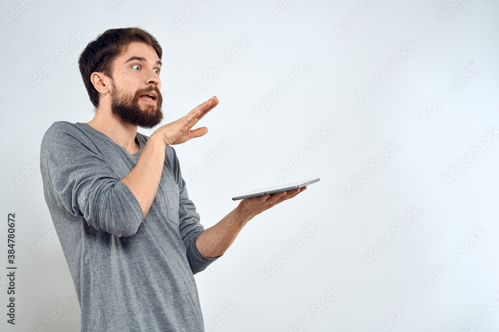 A man with a tablet in his hand internet technology communication gray jacket light background A man with a tablet in his hand internet technology communication gray jacket light background
