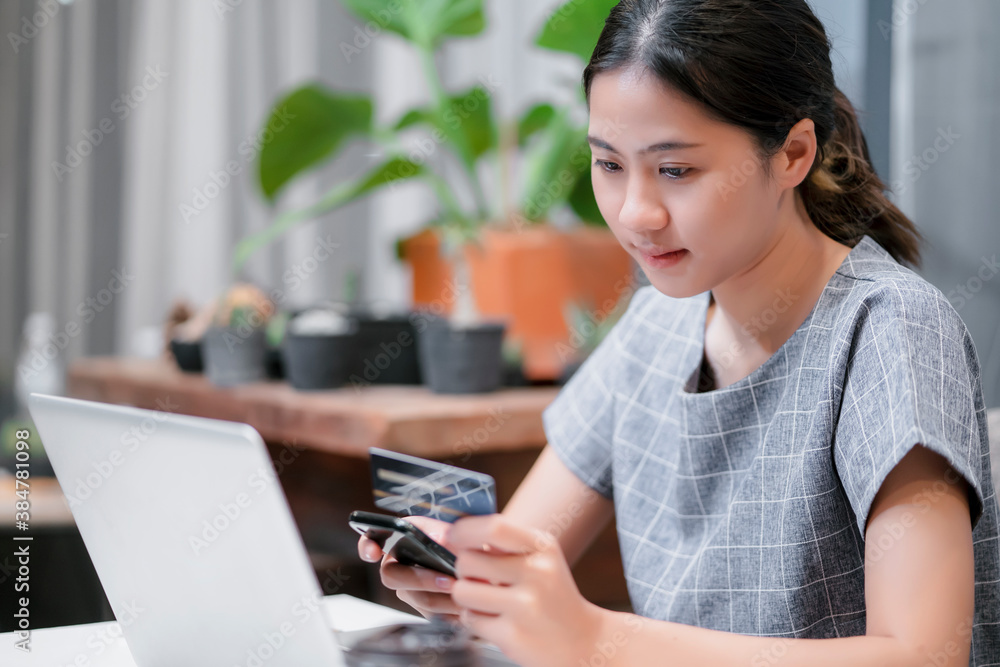 Asian attractive woman home office happy smiling shopping online store ecommerce using smart mobile phone credit card computer laptop filling in billing payment from purchasing products copy space Asian attractive woman home office happy smiling shopping online store ecommerce using smart mobile phone credit card computer laptop filling in billing payment from purchasing products copy space