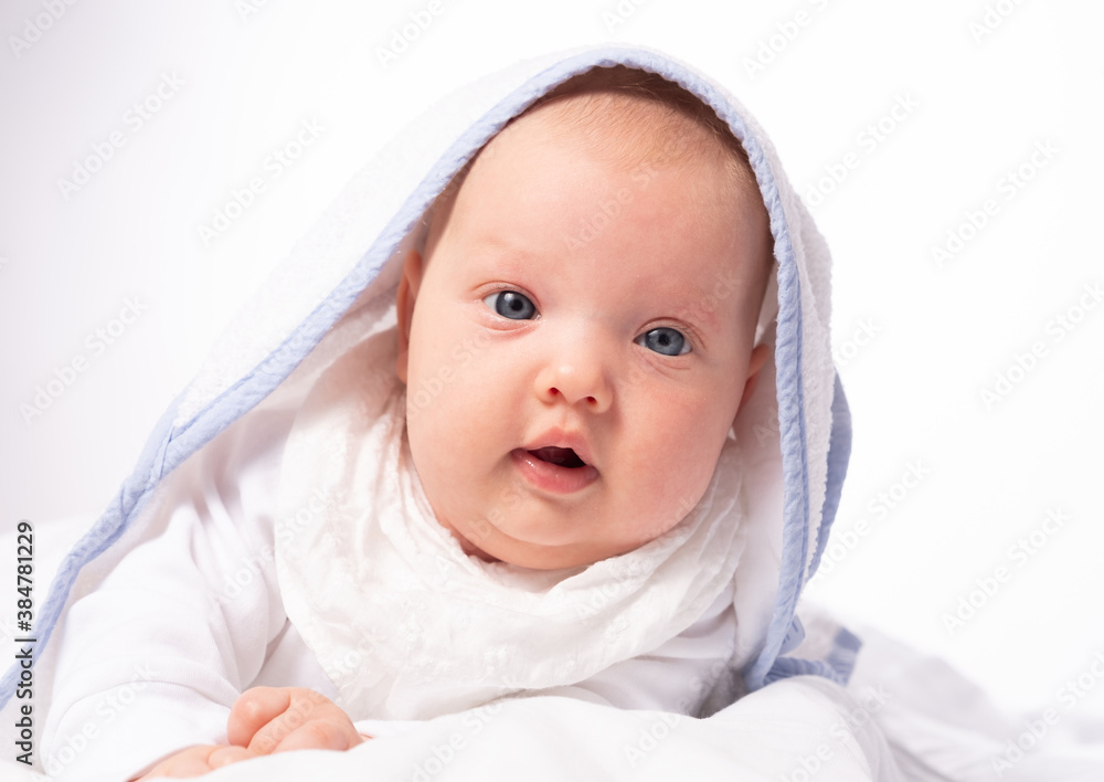 Charming and smiling baby girl lies under a towel after bathing Charming and smiling baby girl lies under a towel after bathing