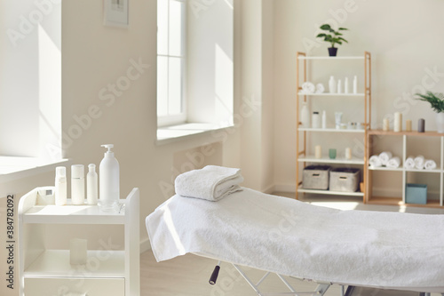 Massage room or beauty parlor with empty bed and ready set of organic skincare products photo