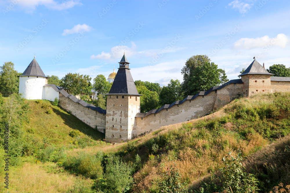 Beautiful summer panoramic view to the fortress wall and tower of Pskov-Pechory Dormition Monastery in Pechory, Pskov region, Russia under blue sky