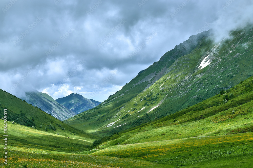 Mountains covered with green grass against the background of clouds