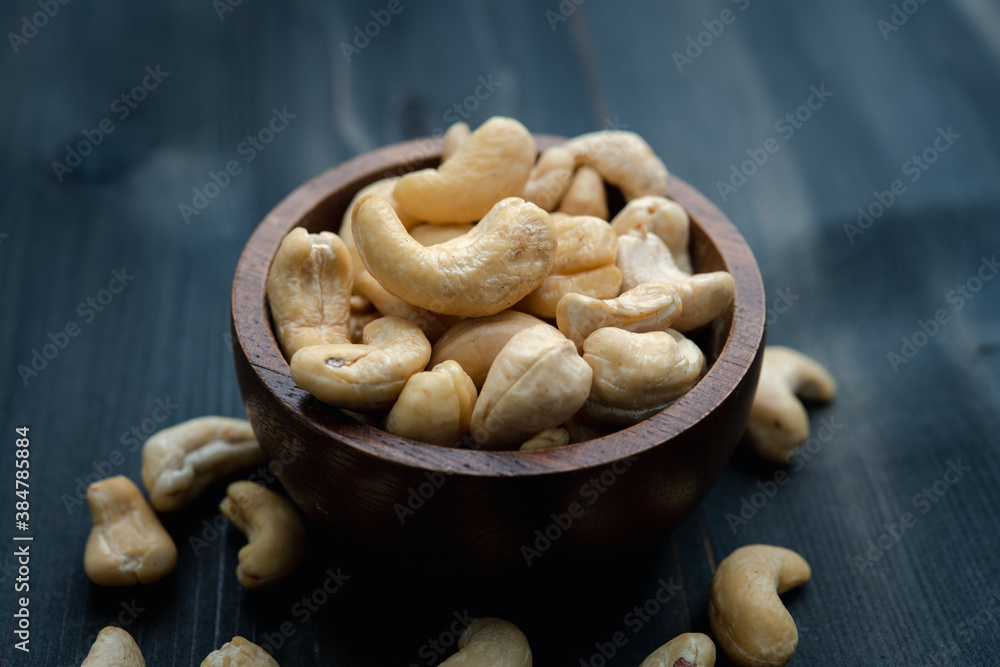 raw cashew nuts in wooden bowl on rustic table, healthy vegetarian snack raw cashew nuts in wooden bowl on rustic table, healthy vegetarian snack