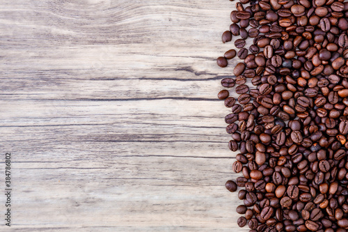 Coffee beans on wooden background. Pile of coffee. Coffee beans on a wooden background. Top view. Copy space.