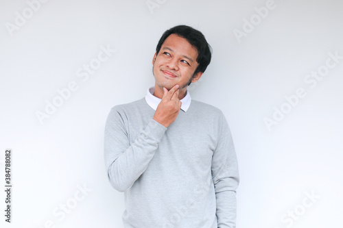 Young Asian man wear grey shirt with thinking and looking idea gesture