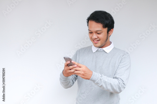 Smart Young asian man is happy and smiling when using smartphone in studio background