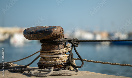 A rusty bollard with ropes. Fishing boats moor here in the port of Santa Pola in Spain. The background is out of focus with nice bokeh. photo