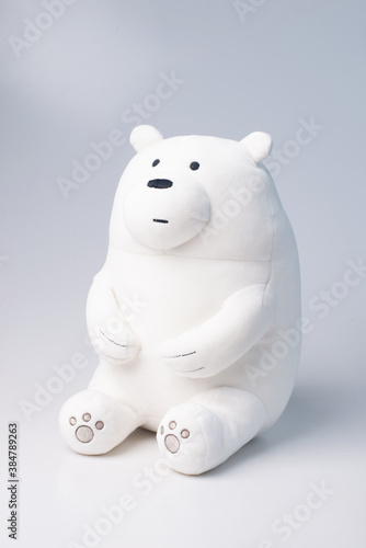 White polar toy bear sits and looks at the light. Gray background. Cute plush toy © YarikL