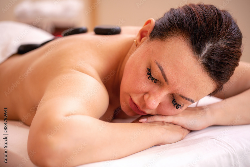 Middle aged woman having a basalt volcanic stone treatment in beauty salon Middle aged woman having a basalt volcanic stone treatment in beauty salon