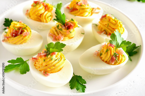Deviled stuffed eggs with egg yolk, bacon, mustard and parsley