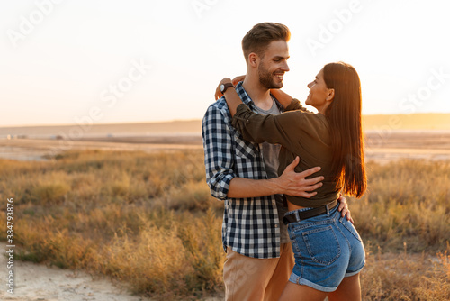 Romantic happy couple hugging and smiling while strolling on nature