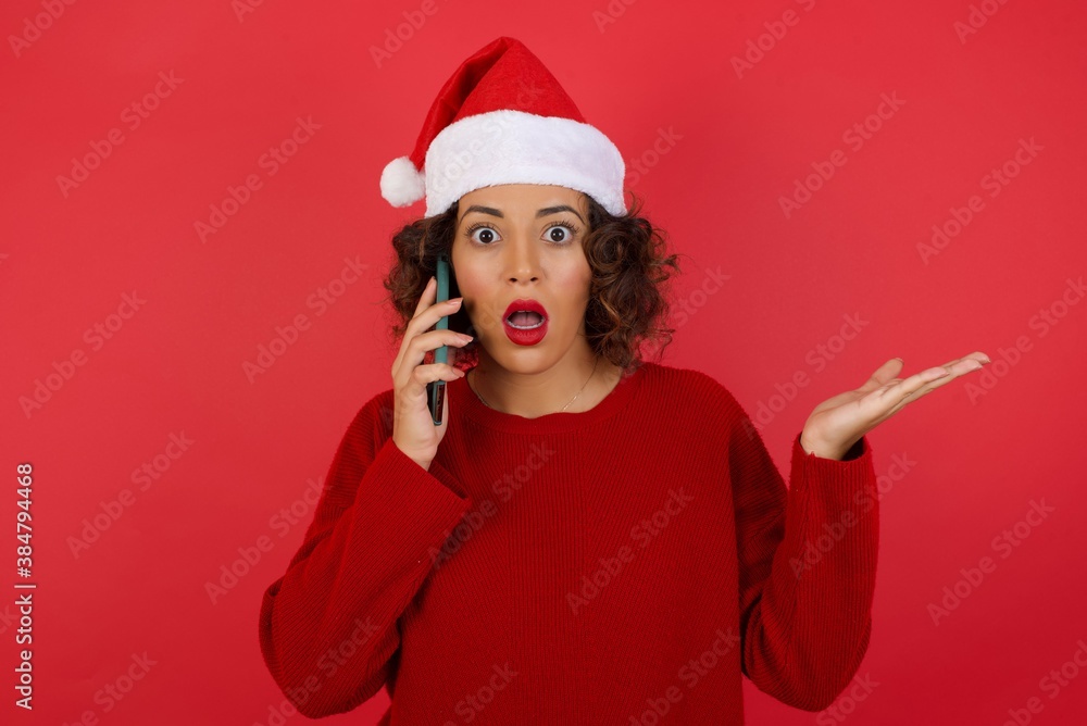 Young woman wearing Christmas hat talking on the phone over isolated background stressed with hand on face, shocked with shame and surprise face, angry and frustrated. Fear and upset for mistake. Young woman wearing Christmas hat talking on the phone over isolated background stressed with hand on face, shocked with shame and surprise face, angry and frustrated. Fear and upset for mistake.