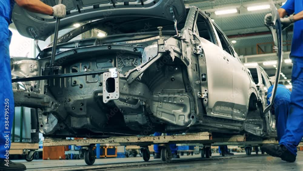 Several workers assembling cars on an assembly line of a car production factory. Several workers assembling cars on an assembly line of a car production factory.