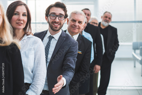 close up. friendly business man standing among his colleagues.