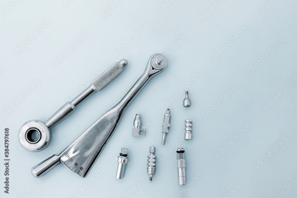 Dental implantation tools: reversible key, torque wrench on a blue background. Dental implantation tools: reversible key, torque wrench on a blue background.