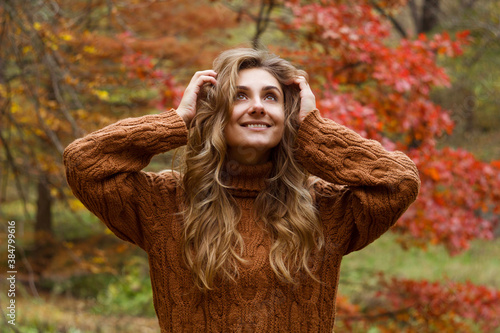 Young happy beautiful woman with curly hair wearing  sweather having good time in autumn park photo