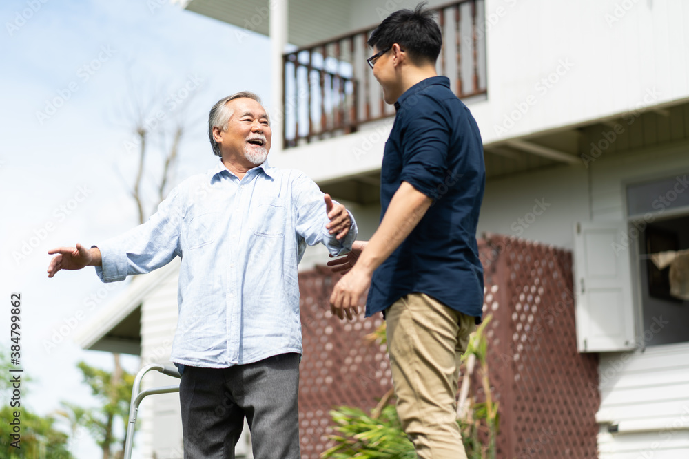 Elderly Asian father and Adult son walking in backyard. Positive Asian man caregiver helping patient Elderly Asian father and Adult son walking in backyard. Positive Asian man caregiver helping patient