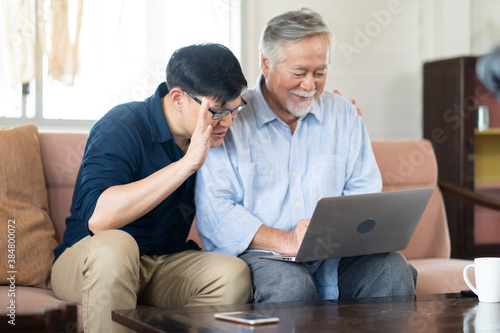 Senior Asian father and adult grown son having video call on laptop computer.