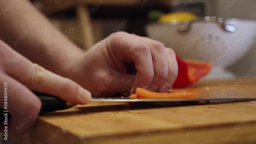 Chef slices big red pepper on the cutting board, in the kitchen. Slow motion. Chef slices big red pepper on the cutting board, in the kitchen. Slow motion.
