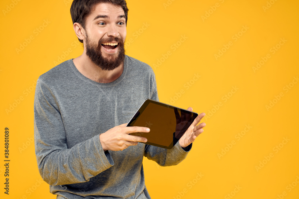Emotional man with tablet in hands technology internet device lifestyle yellow background Emotional man with tablet in hands technology internet device lifestyle yellow background
