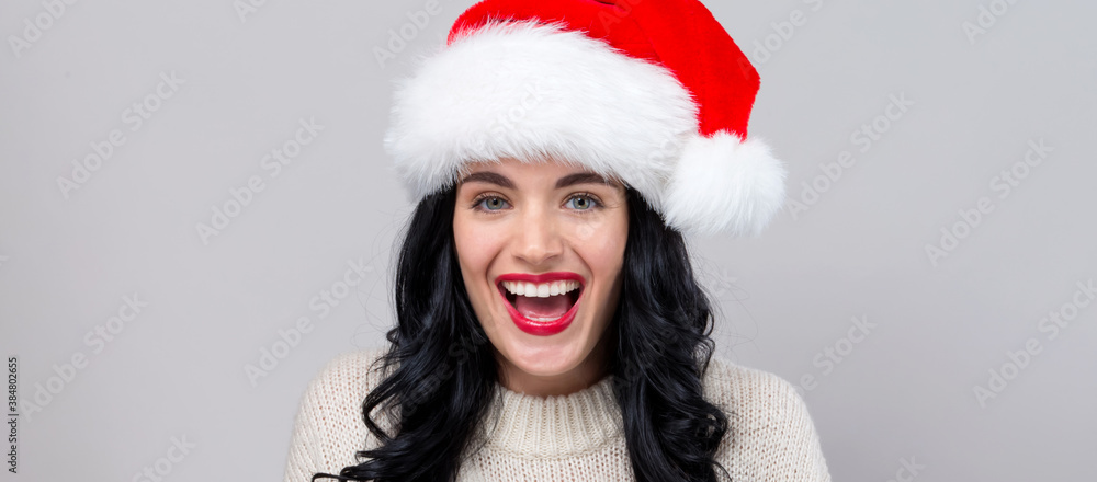 Happy woman with a Santa hat on a gray background Happy woman with a Santa hat on a gray background