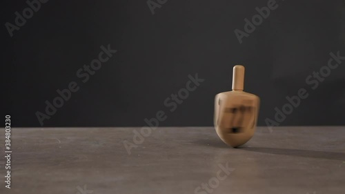 Man spinning dreidel on table against dark background