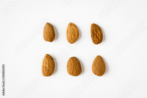 Rows of raw almonds on white background