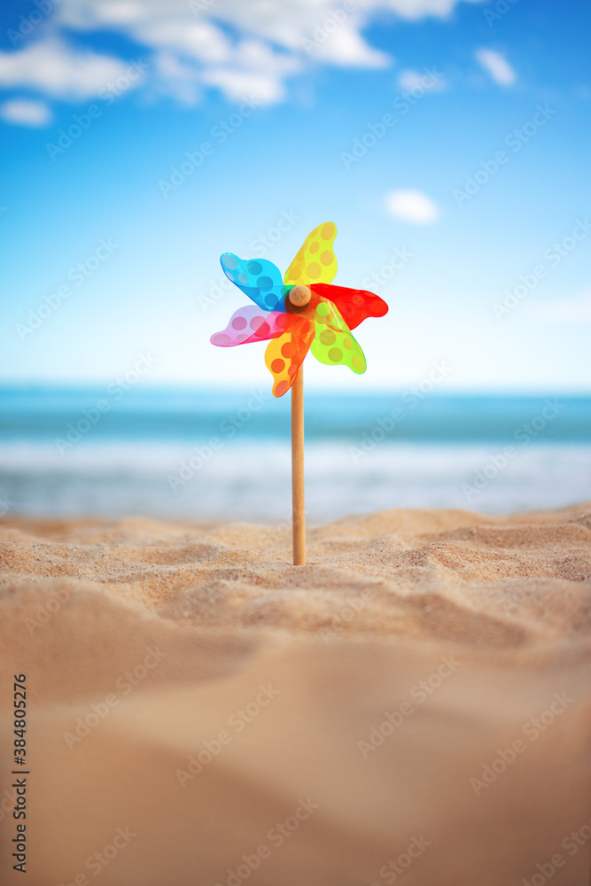 Pinwheel on a beach sand against blue sky and sea, summer vacation