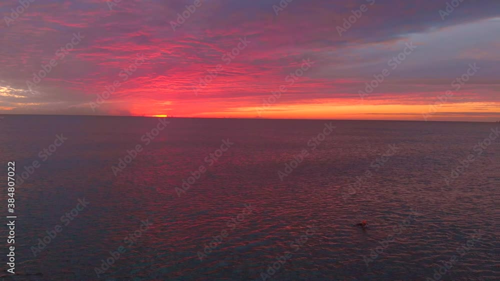 Aerial shot of a swimmer in a beautiful and colorful sunrise entering the Mediterranean Sea. Valencia. Concept freedom, natural sport, free swimming. Aerial shot of a swimmer in a beautiful and colorful sunrise entering the Mediterranean Sea. Valencia. Concept freedom, natural sport, free swimming.
